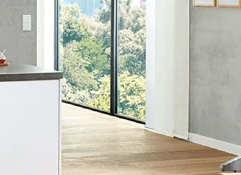 Frau sitzt in der Wohnküche am Laptop und trinkt Tee. Im Hintergrund die Heißwasser-Armatur Grohe Red.